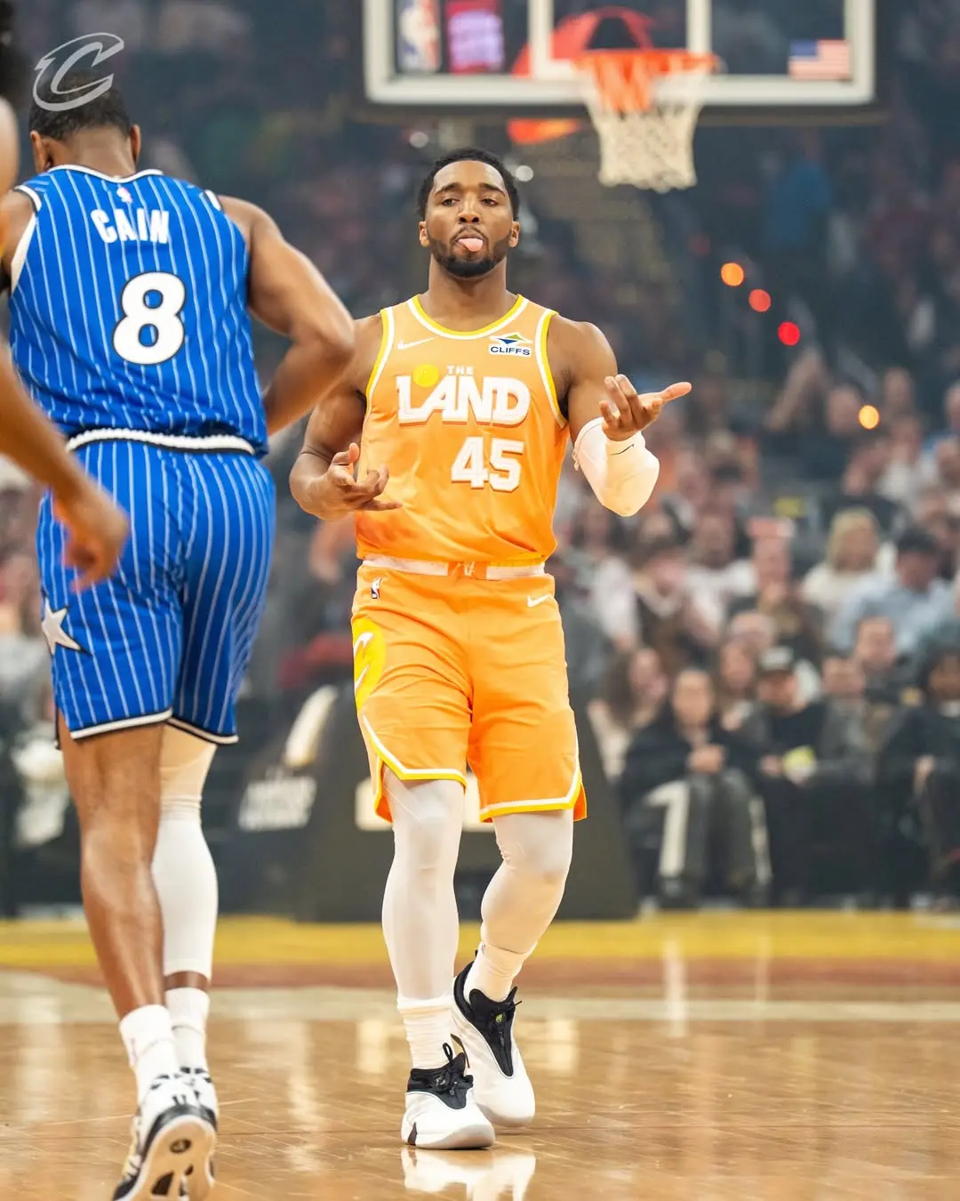 Saveclipapp_656321321_18583460029048717_3147074172736224469_n - the game Basketball player in orange The LAND jersey #45 gesturing with hands, facing a blue defender wearing #8 on a crowded court.