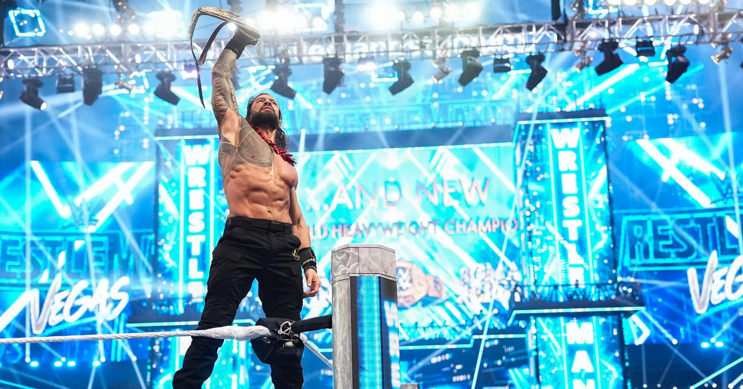 Muscular wrestler with long hair raises a championship belt overhead from the ring ropes in a neon-lit arena.