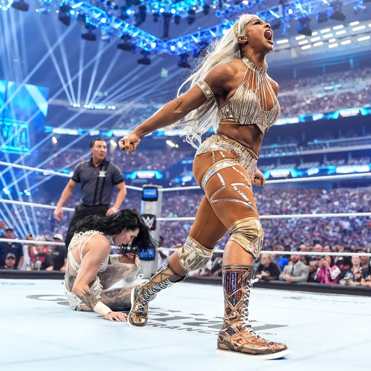 Jade - the game WWE-style female wrestler in gold attire shouting in the ring while an opponent is on the mat, with a cheering arena in the background.
