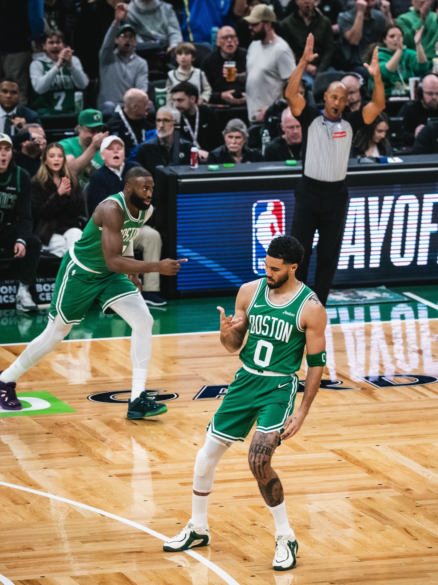 Nba-playoffs - the game Boston Celtics players in green uniforms on a basketball court, one pointing as the crowd cheers in the stands behind them.