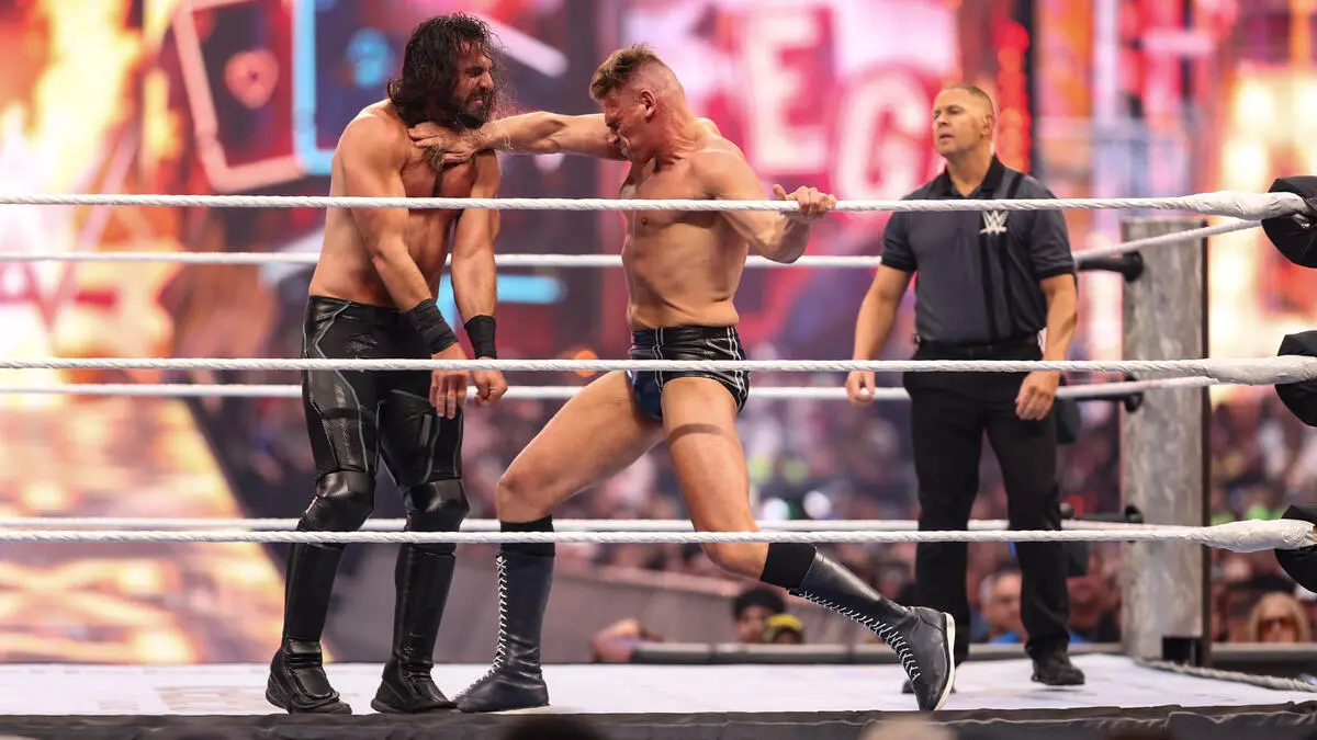 Two muscular wrestlers grapple in the ring as the referee watches.