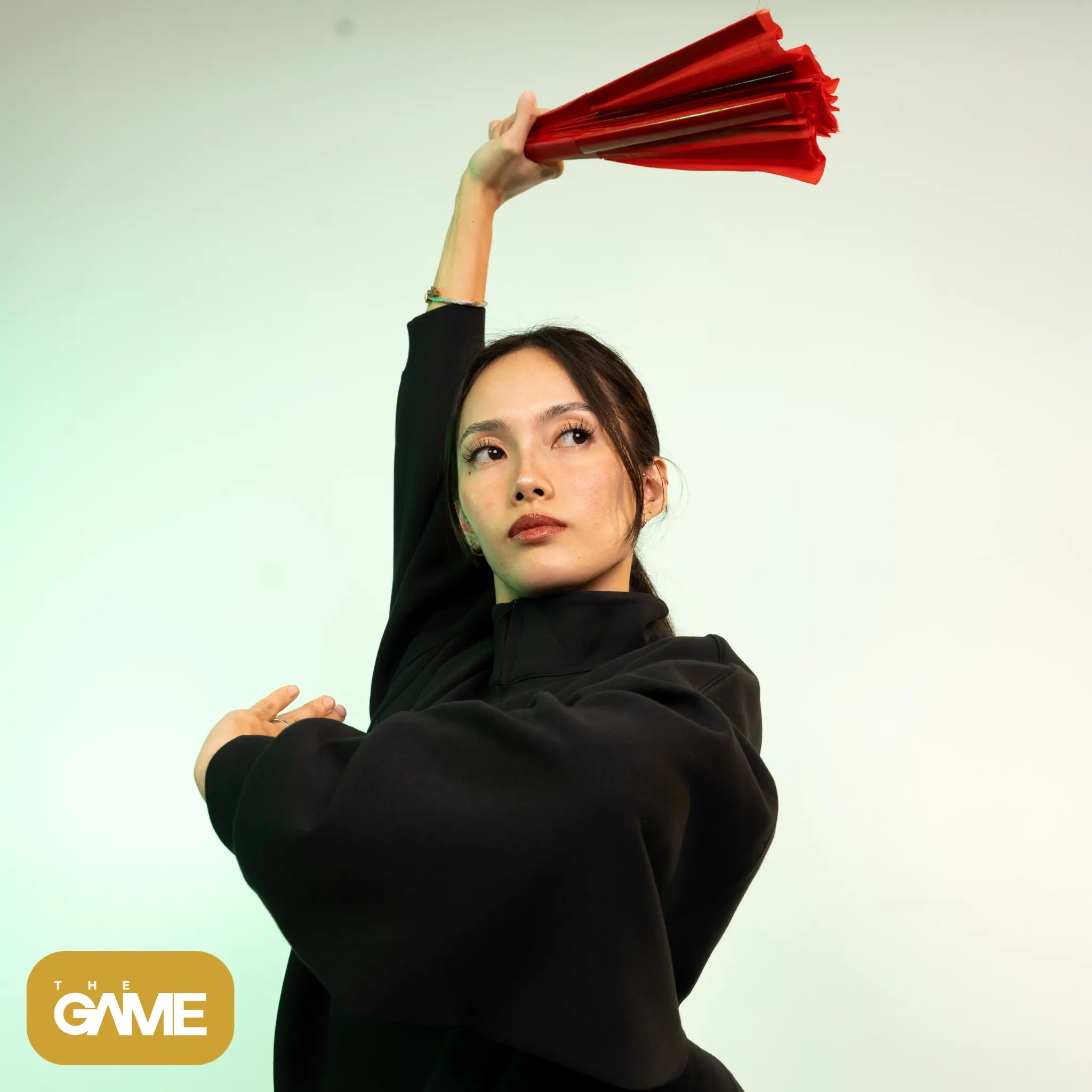4 5 - the game Person raises a red umbrella-like object above their head against a pale background, with a gold logo in the bottom-left corner.