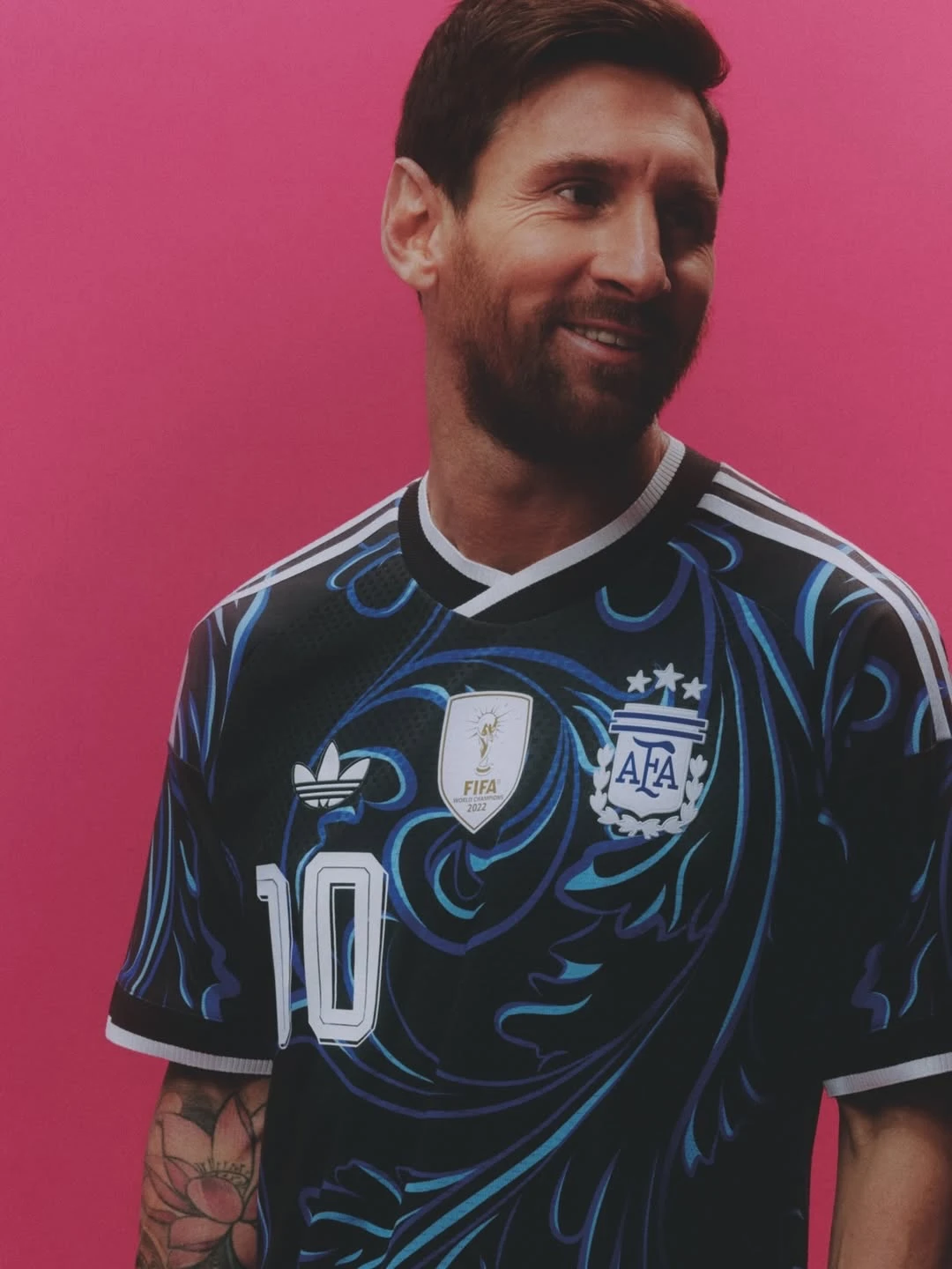 Argentina away - the game Man with short dark hair and beard wearing a dark blue Argentina soccer jersey with the number 10, against a bright pink background.
