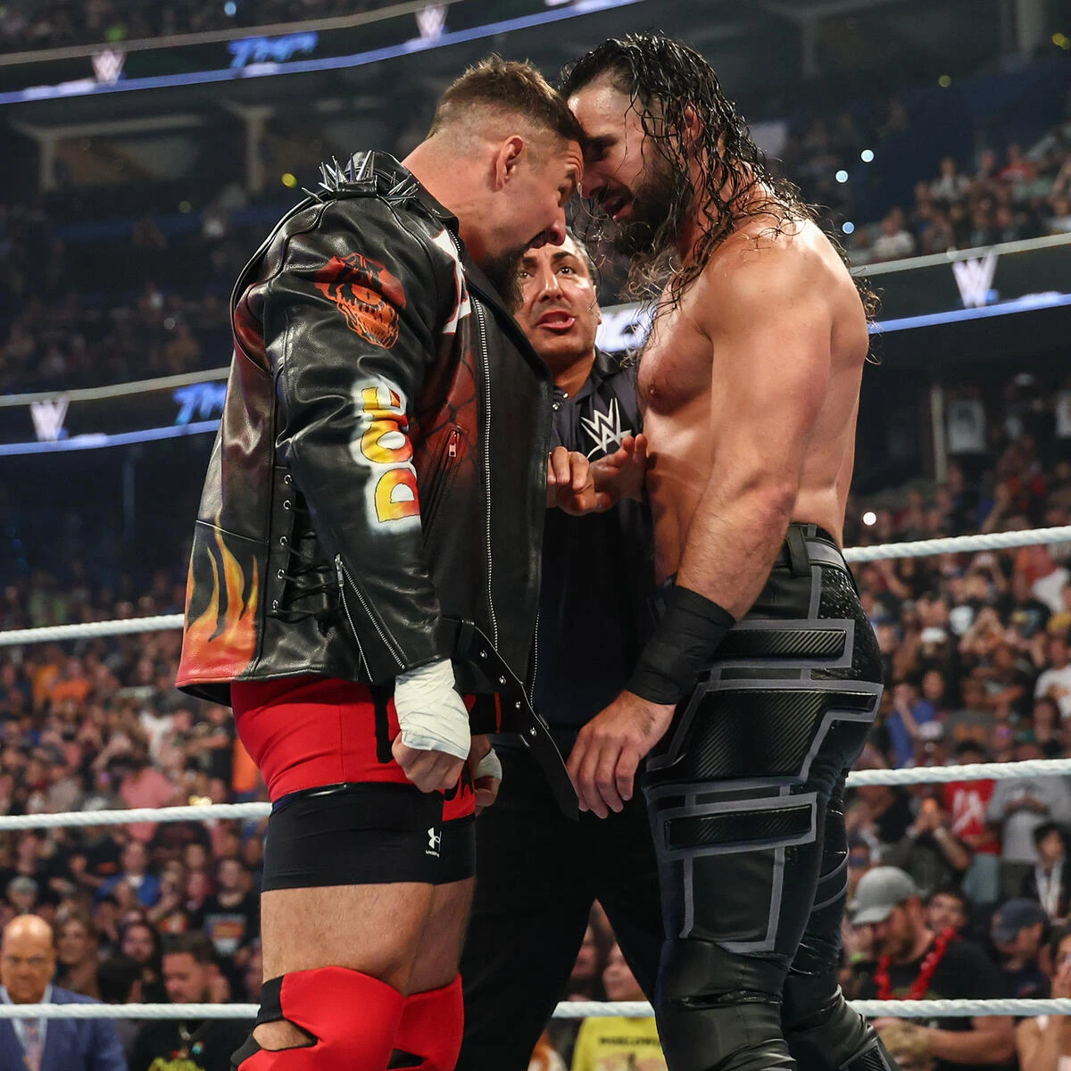 Bron vs seth - the game Two WWE wrestlers face off inches apart in the ring while a referee looks on during a tense moment.