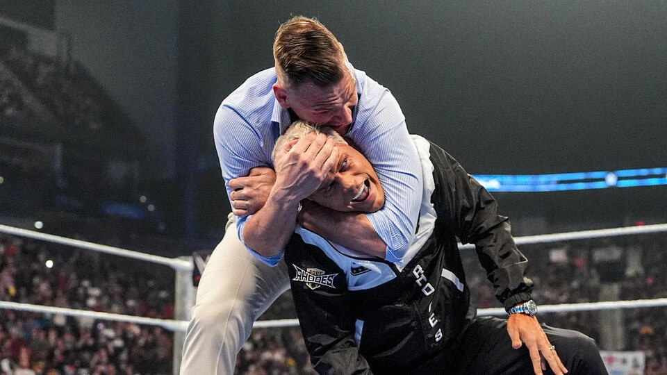 Cody vs gunther - the game Two male wrestlers struggle in the ring, one in a light blue shirt pinning the other in a black jacket as the crowd watches long-side.