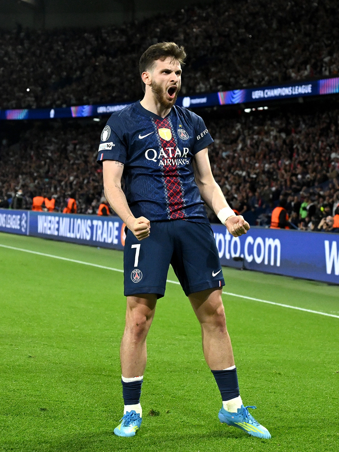 Khvicha kvaratskhelia - the game A male soccer player in a PSG jersey (#7) celebrates on the field, fists clenched and mouth open in a roar.